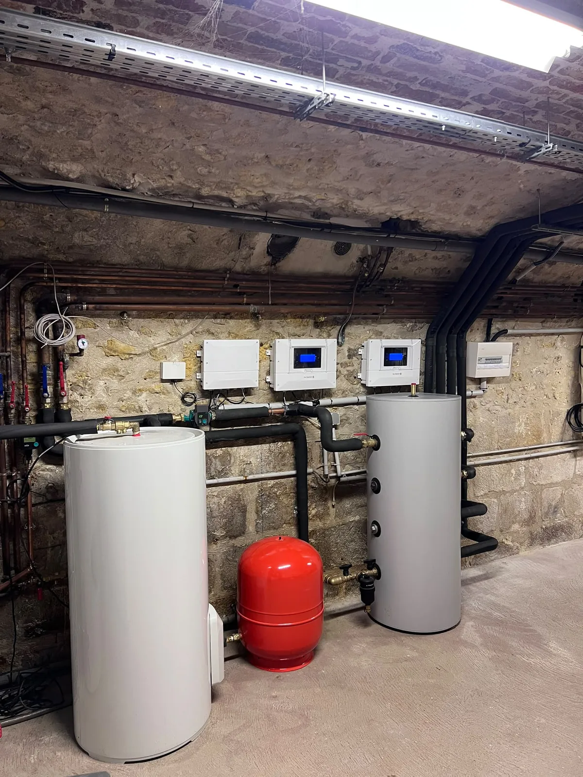 Local technique voûté à Brie-Comte-Robert : modules intérieurs des deux pompes à chaleur De Dietrich, ballon tampon, vase d'expansion et liaisons isolées.