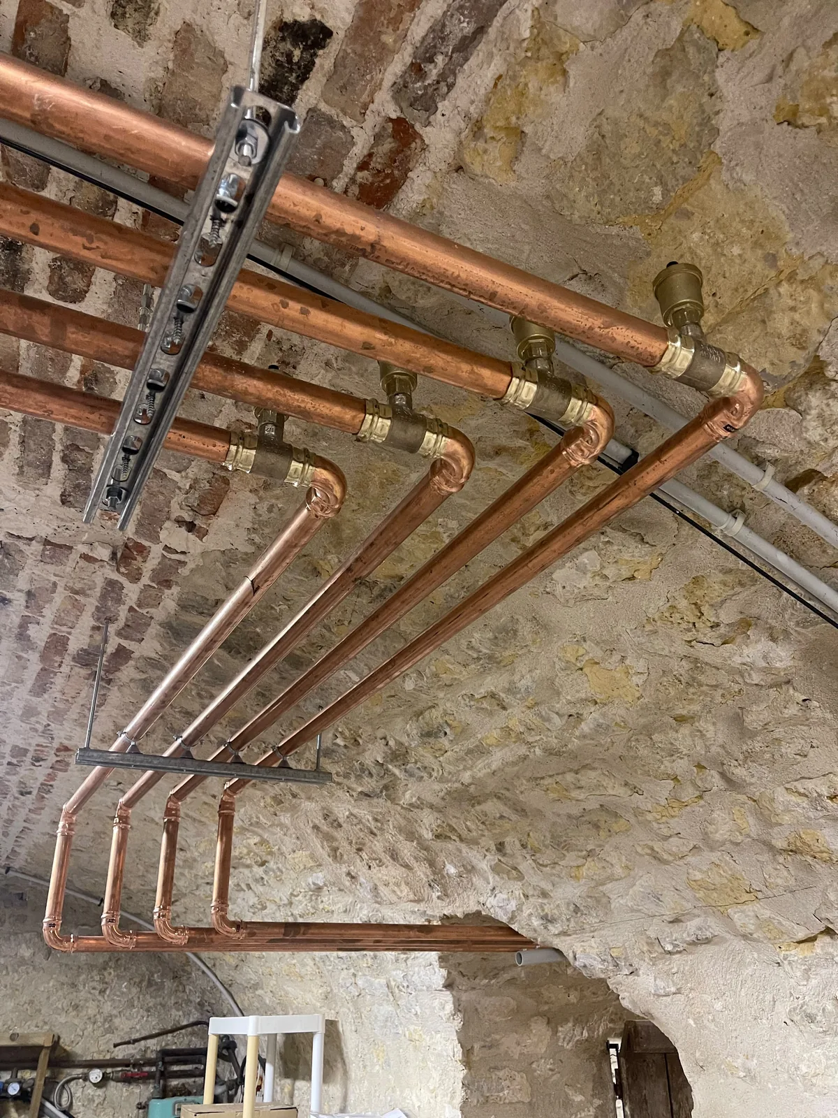 Réseau de tuyauteries en cuivre posé sous la voûte du sous-sol pour relier les deux pompes à chaleur air-eau, chez notre client à Brie-Comte-Robert.